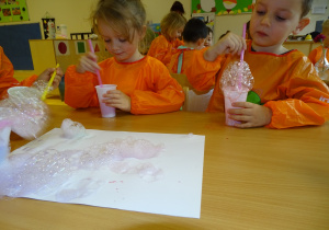 17 Dzieci kolorową pianę przekładają na biały karton tworząc obrazek